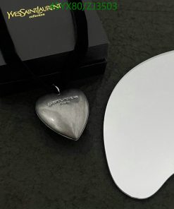 Heart-shaped pendant with black box on marble surface.