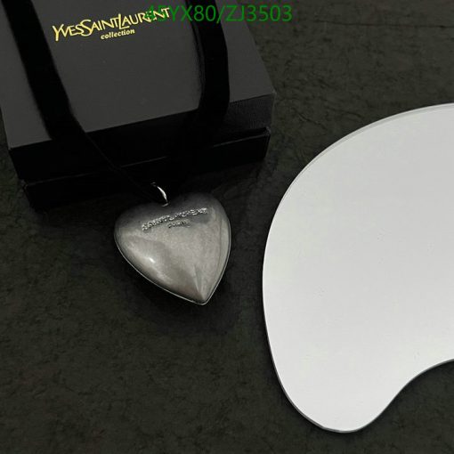 Heart-shaped pendant with black box on marble surface.