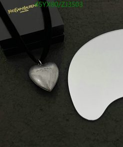 Silver heart pendant with black box and white surface.