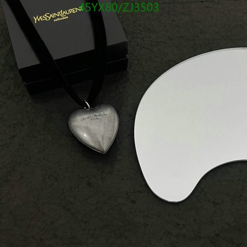 Silver heart pendant with black box and white surface.