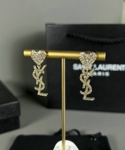 Designer heart-shaped diamond snake earrings on display stand.