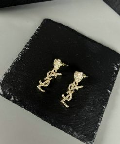 Gold dollar sign stud earrings on black surface.