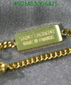 Gold designer necklace with tag on fabric.