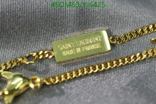 Gold designer necklace with tag on fabric.