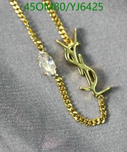 Gold pendant necklace with gemstone on satin fabric.