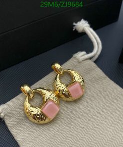 Gold hoop earrings with pink stones on fabric.