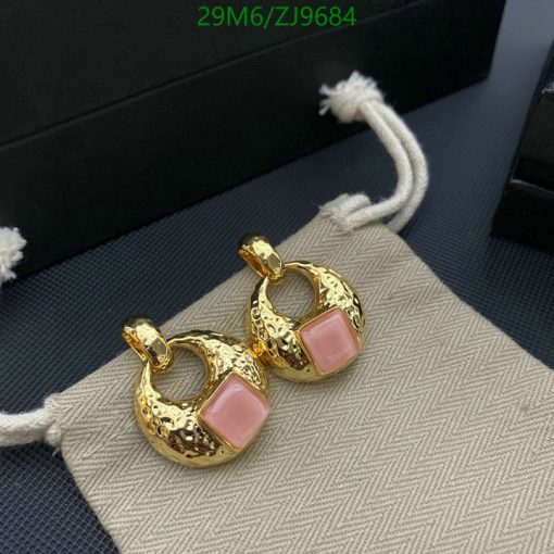 Gold hoop earrings with pink stones on fabric.