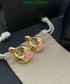 Gold hoop earrings with pink stones on fabric.