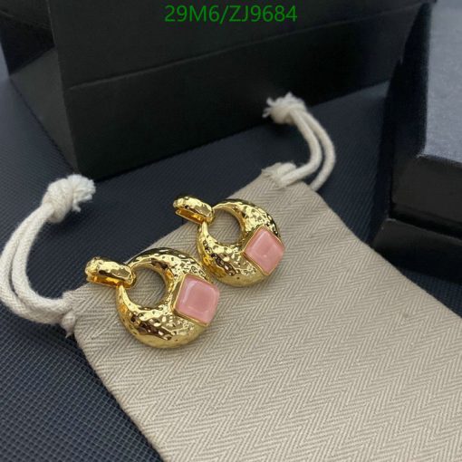 Gold hoop earrings with pink stones on fabric.