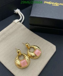 Gold hoop earrings with pink stone on fabric surface.