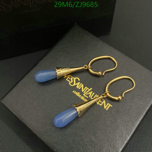 Gold earrings with blue pendant on black box.