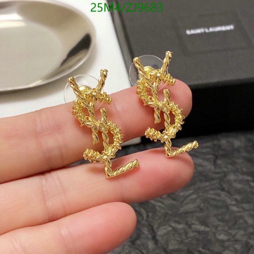 Gold twig-shaped earrings on finger.