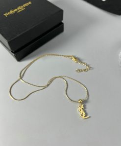 Gold anchor pendant necklace on white surface