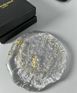 Gold necklace on textured dish, luxury branding.