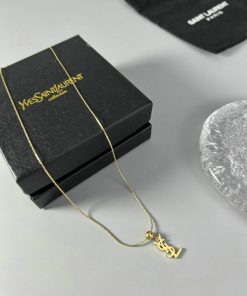 Gold pendant necklace beside designer box.