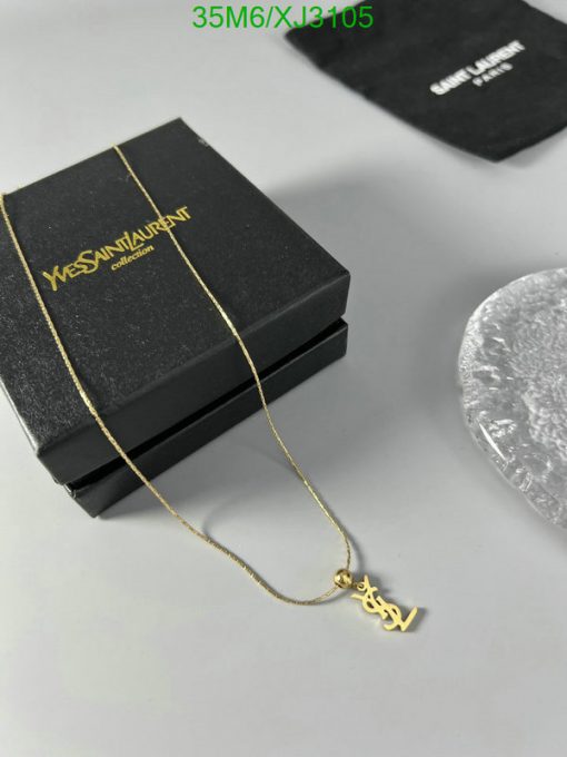 Gold pendant necklace beside designer box.