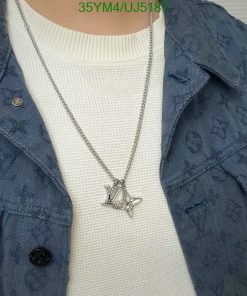 Person wearing designer monogrammed jacket and pendant necklace.