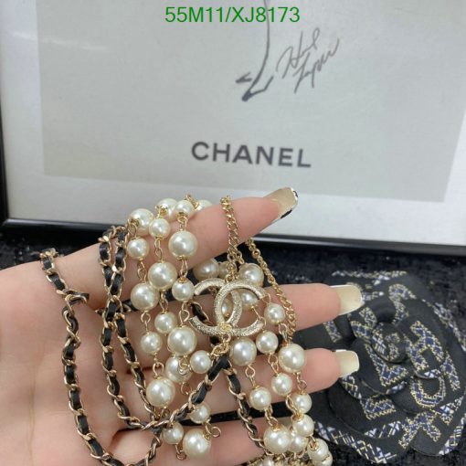 Holding Chanel pearl bracelet and necklace with signature.