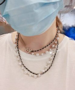 Person wearing layered necklaces and surgical mask.