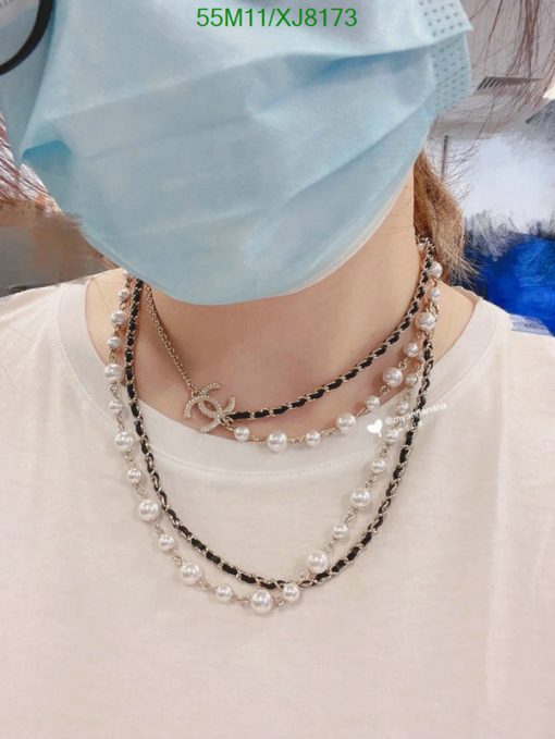 Person wearing layered necklaces and surgical mask.