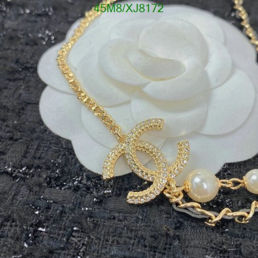 Gold necklace with pearl accents on floral background.