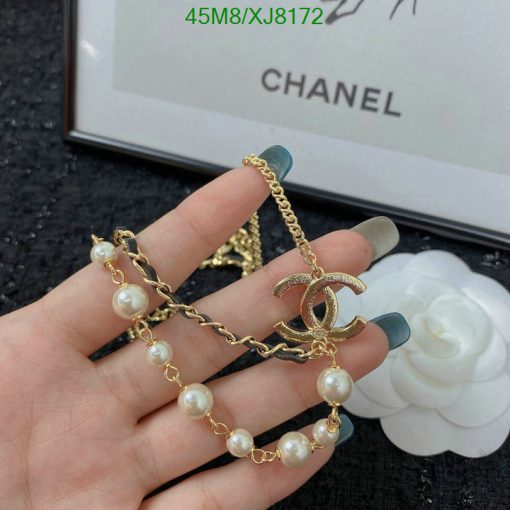 Hand holding pearl gold bracelet with designer logo.