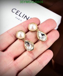 Gold pearl teardrop earrings in hand.