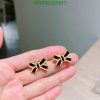 Gold and black bow-shaped earrings in hand.