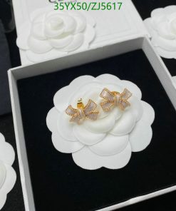 White flower earrings with gold bow detail in box.