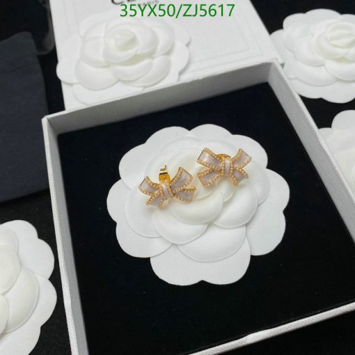 White flower earrings with gold bow detail in box.