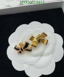 Gold and black bow-shaped earrings on white flower display.