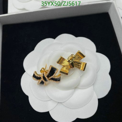 Gold and black bow-shaped earrings on white flower display.