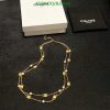 Gold necklace with pearls on black surface near box.