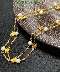 Gold chain necklace with pearls on black surface.