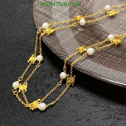 Gold chain necklace with pearls on black surface.