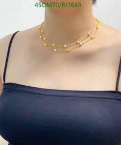 Woman wearing layered gold necklaces with pearls.