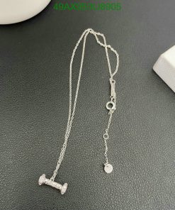 Silver barbell pendant necklace on dark surface.