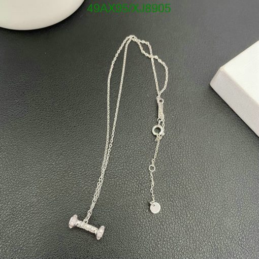 Silver barbell pendant necklace on dark surface.