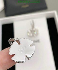 Silver designer logo pendant held by a finger.