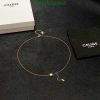 Celine gold bracelet on dark background with packaging.