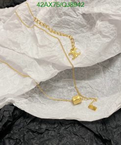 Gold necklace with charm on wrinkled paper.