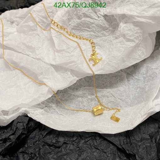 Gold necklace with charm on wrinkled paper.