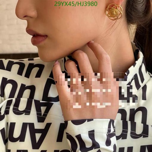 Woman wearing patterned blouse and earring.