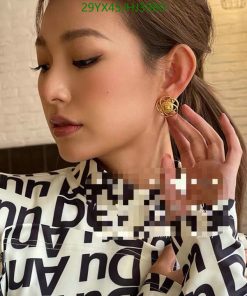 Woman showcasing designer earring and patterned shirt.