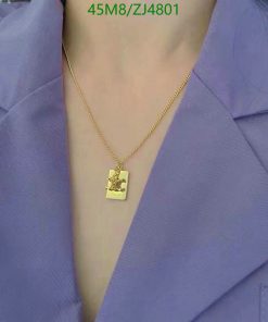 Gold necklace with pendant on person wearing purple blouse.