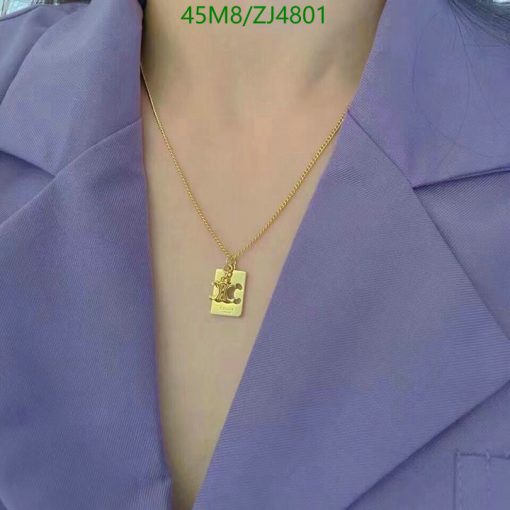 Gold necklace with pendant on person wearing purple blouse.