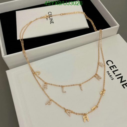 Gold necklace with letter pendants on branded box.