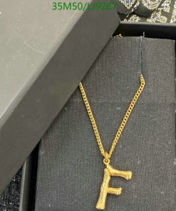 Gold "F" pendant on chain beside box.