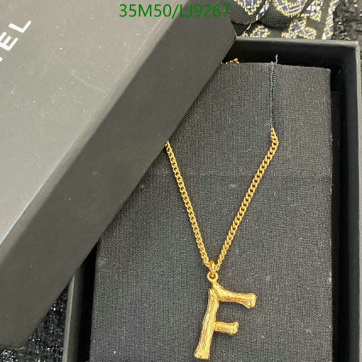 Gold "F" pendant on chain beside box.