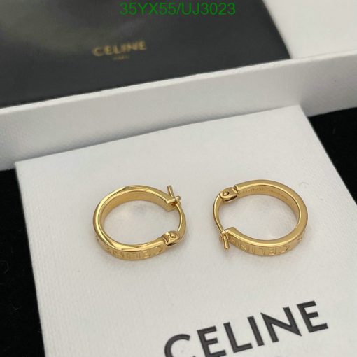 Gold hoop earrings on white display with luxury branding.